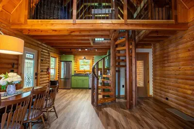 a kitchen and dining room with a spiral staircase in a log cabin at Diamond Creek | Sleeps up to 6 in Gallipolis