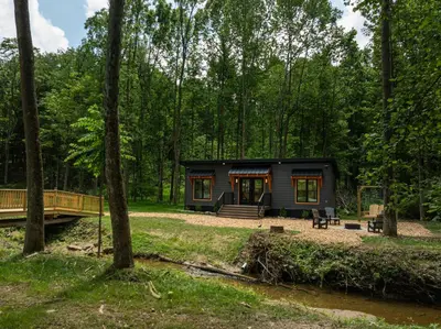 a tiny house in the woods with a bridge at Luxe Studio in Millersburg