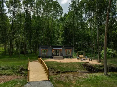 a tiny house in the woods with a wooden bridge at Luxe Studio in Millersburg