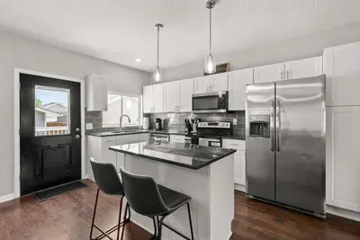 a kitchen with a stainless steel refrigerator and two chairs at The Southern Nook - For 8 in Columbus