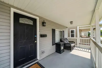 a porch with a black door and a chair at The Southern Nook - For 8 in Columbus