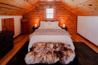 a bedroom with a large bed in a wooden cabin at COZY Cabin with Hot Tub - Near all in Hocking Hills in Logan