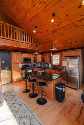 a kitchen with a counter and chairs in a cabin at COZY Cabin with Hot Tub - Near all in Hocking Hills in Logan