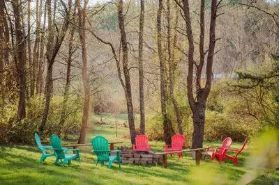 a group of chairs sitting around a table in the grass at COZY Cabin with Hot Tub - Near all in Hocking Hills in Logan