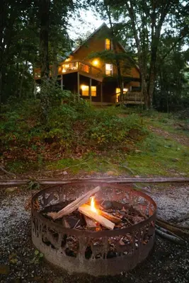 a fire pit in front of a house at Cheerful Two Bdrm Cabin with Hot Tub & Pet Friendly in Rockbridge