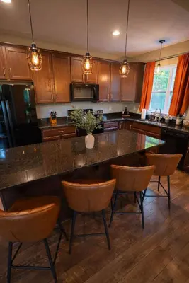 a kitchen with a large island with bar chairs at Modern 2 BD cabin with hot tub & Games & Central Loc in Rockbridge