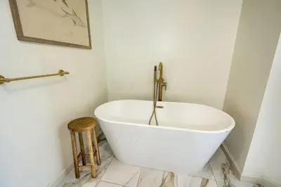 a white bath tub in a bathroom with a wooden stool at Buckingham Woods I Hocking Hills in Logan