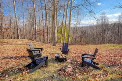 three chairs sitting next to a fire in a field at Buckingham Woods I Hocking Hills in Logan