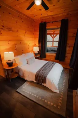 a bedroom with a bed in a log cabin at Memories at Hillside A Modern Cabin Hocking Hills in McArthur