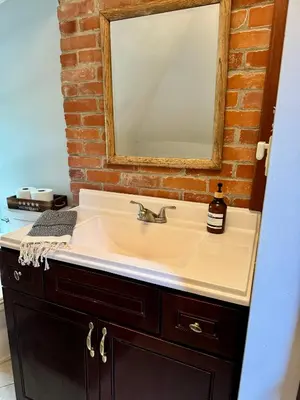 a bathroom sink with a mirror on a brick wall at Jungle House Luxury Stays - Columbus Downtown Short North in Columbus
