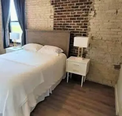 a bedroom with a white bed and a brick wall at Jungle House Columbus Downtown Free Parking Sleeps 8 - Steps to Convention Center & Nationwide Arena - 2BR Short North Luxury Home - Over 5,800 Five Star Stays in Columbus