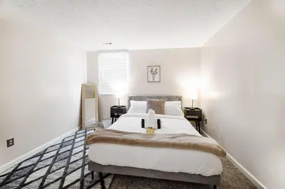 a bedroom with a large bed with white walls at Collins Avenue Duplex – 2 Homes in Columbus