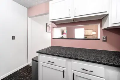 a kitchen with white cabinets and a mirror at Collins Avenue Duplex – 2 Homes in Columbus