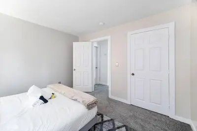 a bedroom with white walls and a bed with white sheets at Collins Avenue Duplex – 2 Homes in Columbus