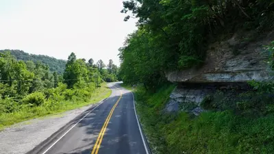an empty road with trees on the side of a mountain at Boons Camp Cabin