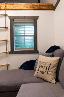 a couch with a pillow that says be our guest at Boons Camp Cabin