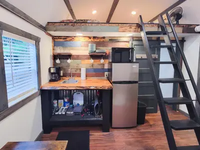 a kitchen in a tiny house with a ladder at Boons Camp Cabin