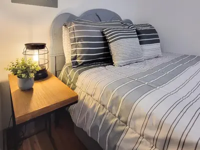 a bed with striped pillows and a table with a lamp at Boons Camp Cabin