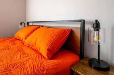 a bed with an orange pillow and a lamp at Relaxed 2BR Apt in Moraine with Office Space and Washer & Dryer in Moraine