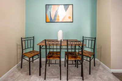 a dining room table with four chairs and a candle on it at Paws & Peace Cozy 1BR Ground Flr Gem in Dayton in Dayton