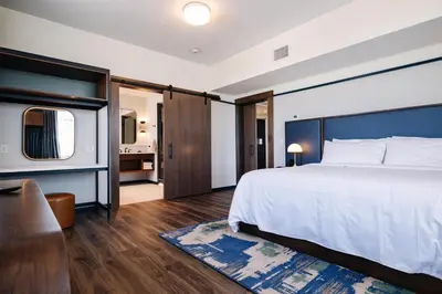 a hotel room with a bed and a living room at The Hotel Rambler Montgomery, Tapestry Collection By Hilton