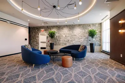 a lobby with blue chairs and a table and a stone wall at The Hotel Rambler Montgomery, Tapestry Collection By Hilton
