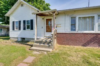 a small white house with a porch and a door at Charming and Convenient Home in Butler