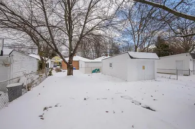 a yard covered in snow with a tree and buildings at South Euclid 3BR Cozy Winter Escape in South Euclid