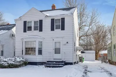 a white house with a white door in the snow at South Euclid 3BR Cozy Winter Escape in South Euclid