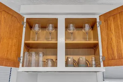 a kitchen cabinet with wine glasses in it at South Euclid 3BR Cozy Winter Escape in South Euclid