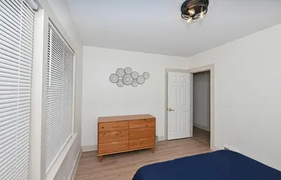 a bedroom with white walls and a bed and a wooden dresser at Cozy 2BR Lyndhurst Retreat in Lyndhurst