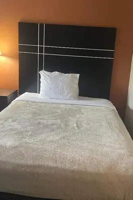 a white bed with a black headboard and a white pillow at Hotel Inn Columbus in Columbus