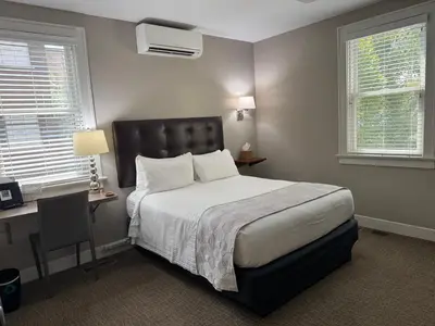 a bedroom with a bed and a desk and two windows at Bexley Bed and Breakfast in Columbus