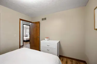 a bedroom with a bed and a dresser and a door at The Family Nook - Home for 8 in Hamilton