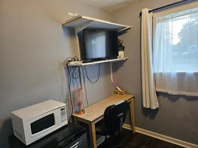 a room with a microwave and a desk with a tv at Navarre Guest Rooms in Columbus