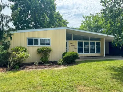 a small yellow house with a yard at Mid-Century Modern Themed Home with Outdoor Hot Tub in Vermilion