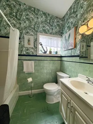 a bathroom with green tiled walls and a toilet and a sink at Mid-Century Modern Themed Home with Outdoor Hot Tub in Vermilion