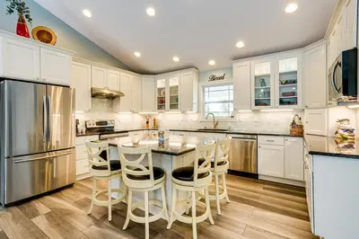 a kitchen with white cabinets and a island with bar stools at 4 Mi to Dtwn Ohio River Valley Home with Deck! in Aurora