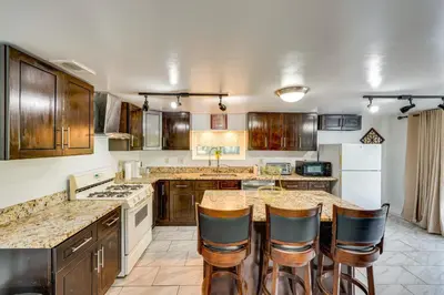 a large kitchen with wooden cabinets and bar stools at Cozy House on Meadowbrook Lake Serene, Scenic! in Stow