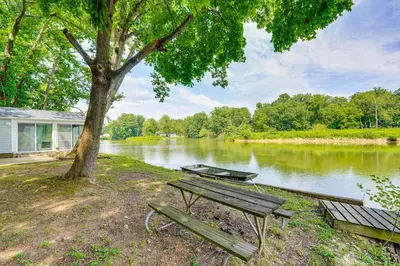 a picnic table and a tree next to a river at Cozy House on Meadowbrook Lake Serene, Scenic! in Stow