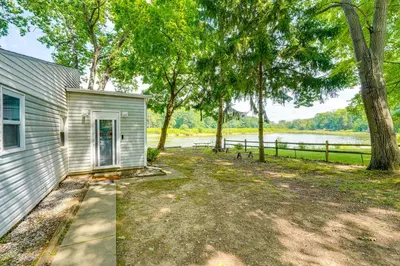a white house with a yard next to a tree at Cozy House on Meadowbrook Lake Serene, Scenic! in Stow