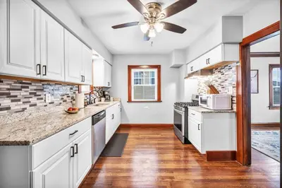 a kitchen with white cabinets and a ceiling fan at Suite Dreams Cleveland in Shaker Heights