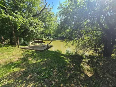 a bench sitting on a wooden platform next to a river at River's Rest on Hocking River in Coolville