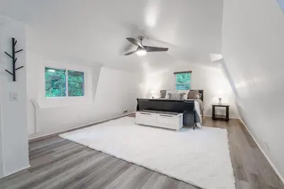 a white living room with a bed and a ceiling fan at Riverstone Cabin and Retreat in West Liberty