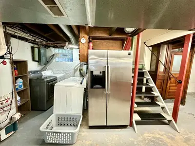 a kitchen with a stainless steel refrigerator and a staircase at The Dayton DreamHouse in Dayton