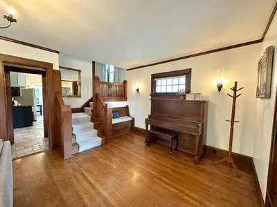 a living room with a piano and a staircase at The Dayton DreamHouse in Dayton