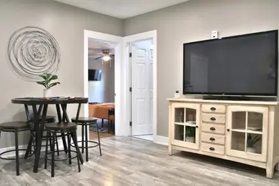 a living room with a television on a stand with a table at Lakewood Entire Home! Sleeps 10! in Lakewood