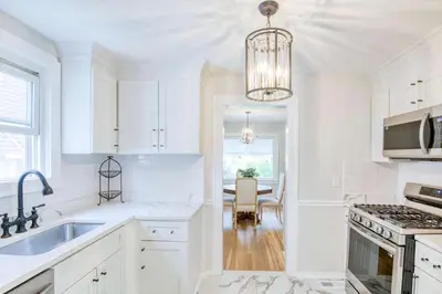 a white kitchen with a sink and a table at Farmhouse Fresh 4BR Retreat in University Heights