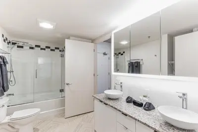 a white bathroom with two sinks and a shower at 4BR Combined Units at Skyline 776 in Cleveland