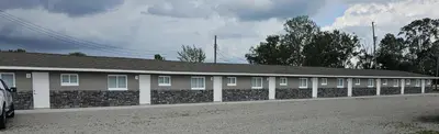 a long building with a stone wall and aphalt at Sunrise Inn LLC in Port Clinton